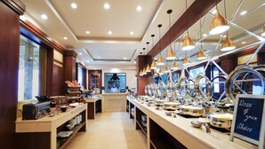 A buffet area with multiple serving stations, a central counter, and a view of the kitchen in the background.