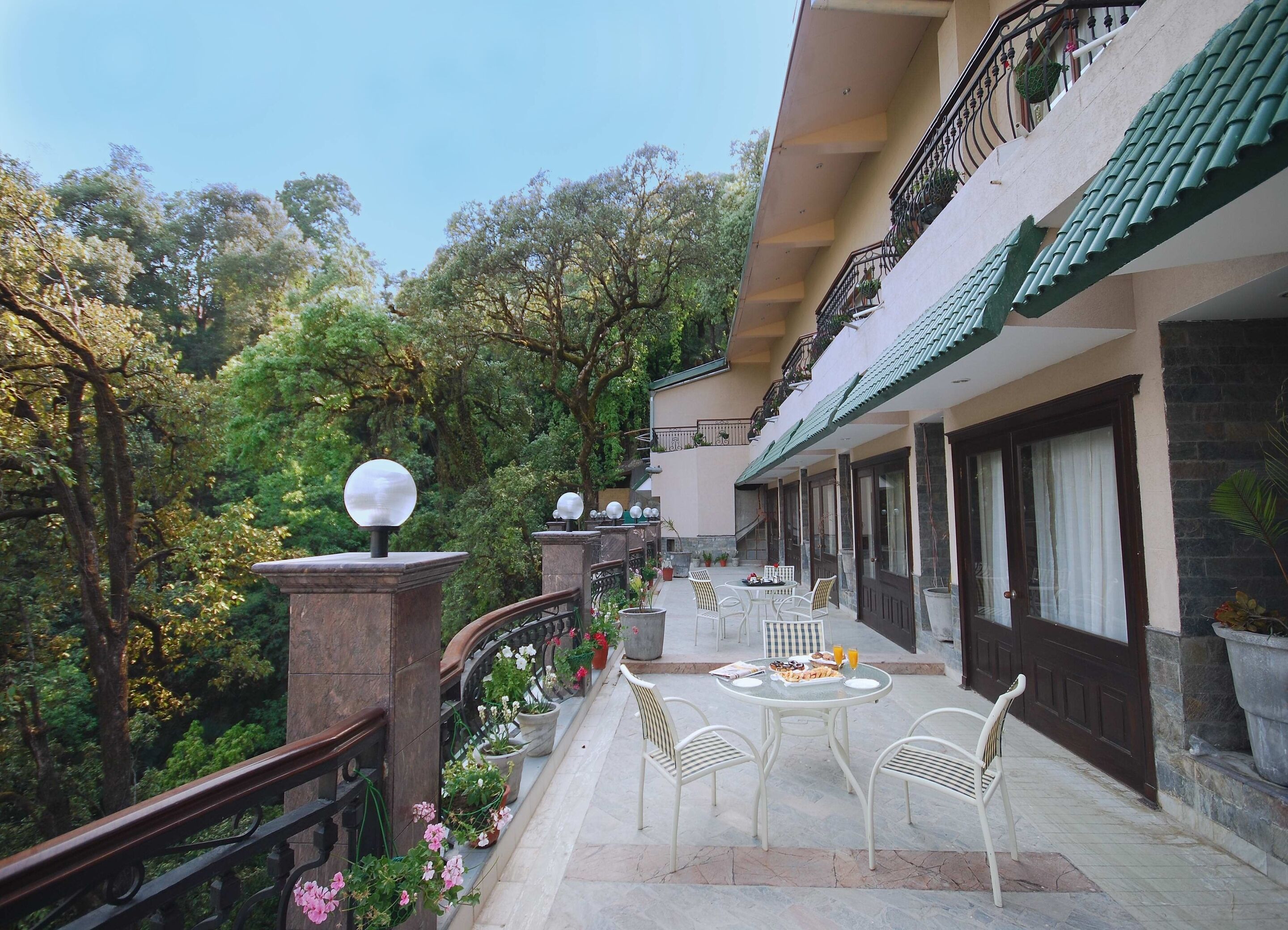 A balcony with a table and chairs, surrounded by potted plants and flowers.