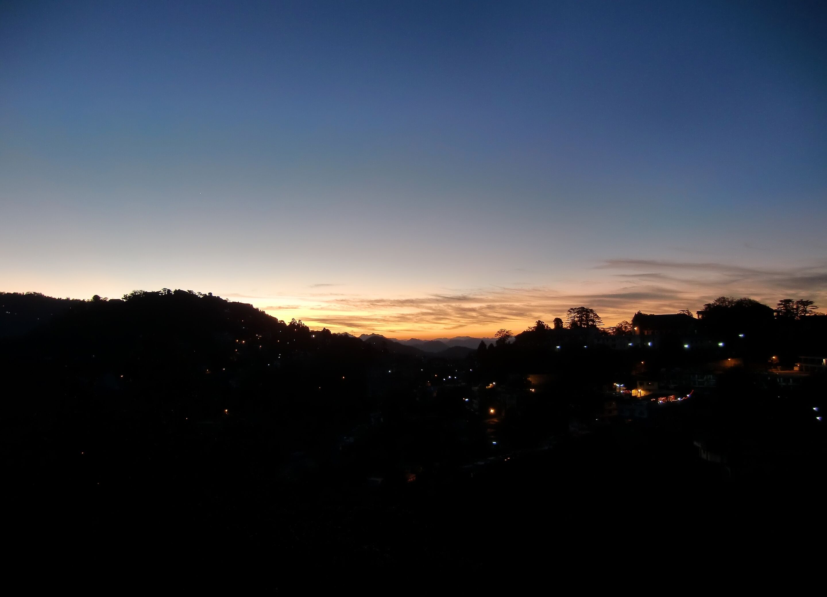 A nighttime view of a town with buildings silhouetted against a twilight sky.