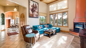 A spacious living room with a large blue sectional sofa, a leather armchair, and a fireplace.