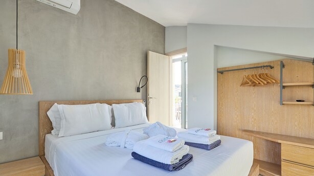 Ett modernt hotellrum med en stor säng, ett träfärgat sänggavel, ett träskrivbord och en trägarderob med en klädstång.