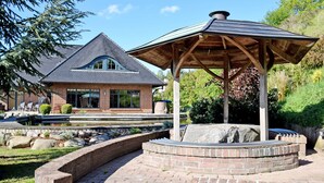 A brick house with a sloped roof and a wooden gazebo in a landscaped garden. - Ferienwohnung mit Terrasse am Hafen in Seedorf 08 - 08 Ferienwohnung mit Terrasse am Hafen in (Sellin)