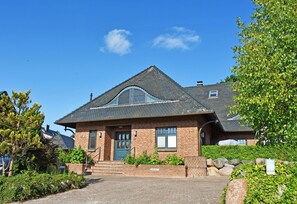 A brick house with a steeply pitched roof, a front door, and a small porch.
