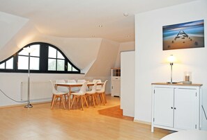 A modern dining area with a high ceiling, a large window, and a painting on the wall.