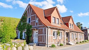 A two-story brick house with a red-tiled roof, a front porch, and a small garden.