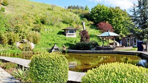 A serene garden with a pond, a gazebo, and a small brick structure.
