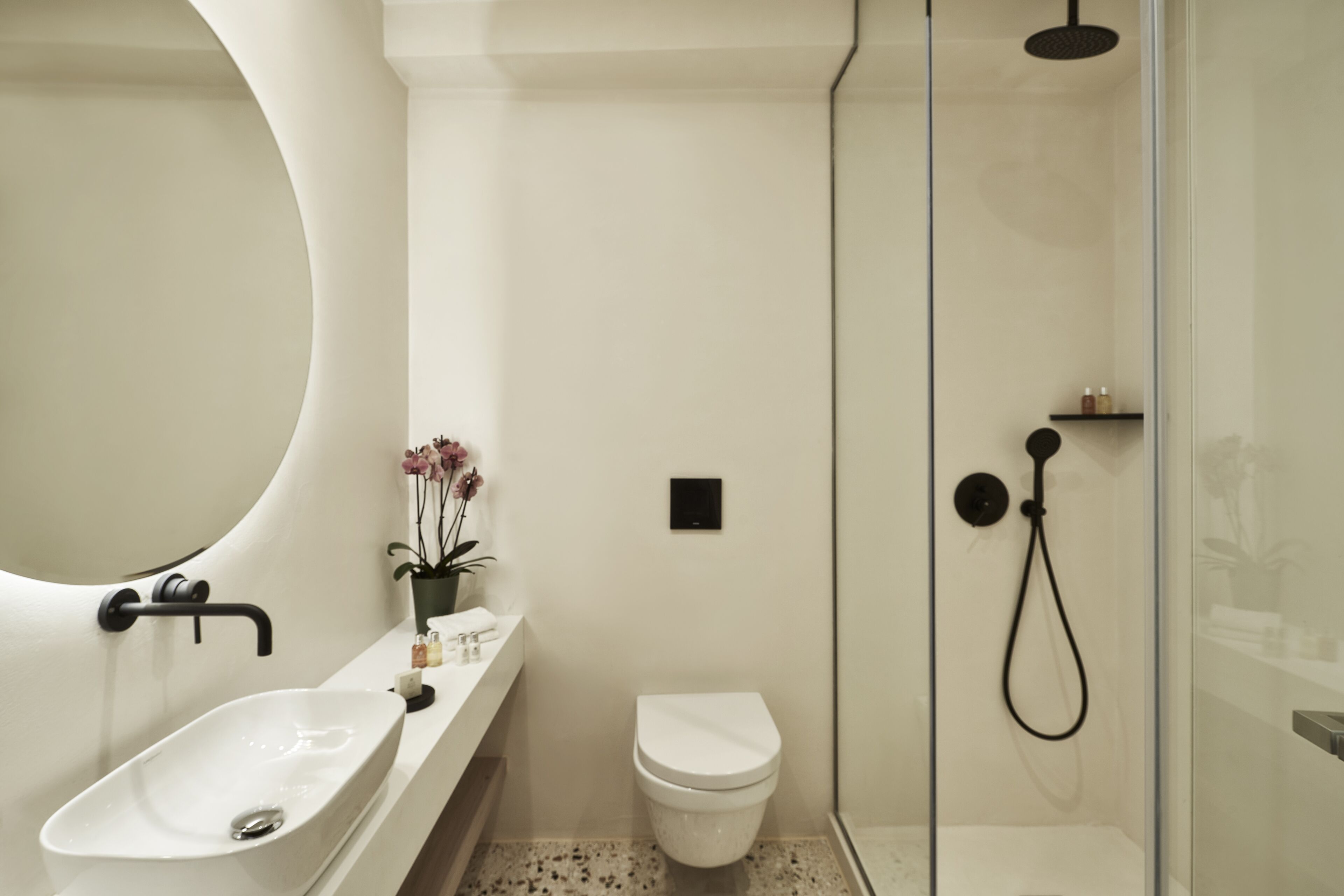 A modern bathroom with a freestanding bathtub, a toilet, and a glass-enclosed shower area.