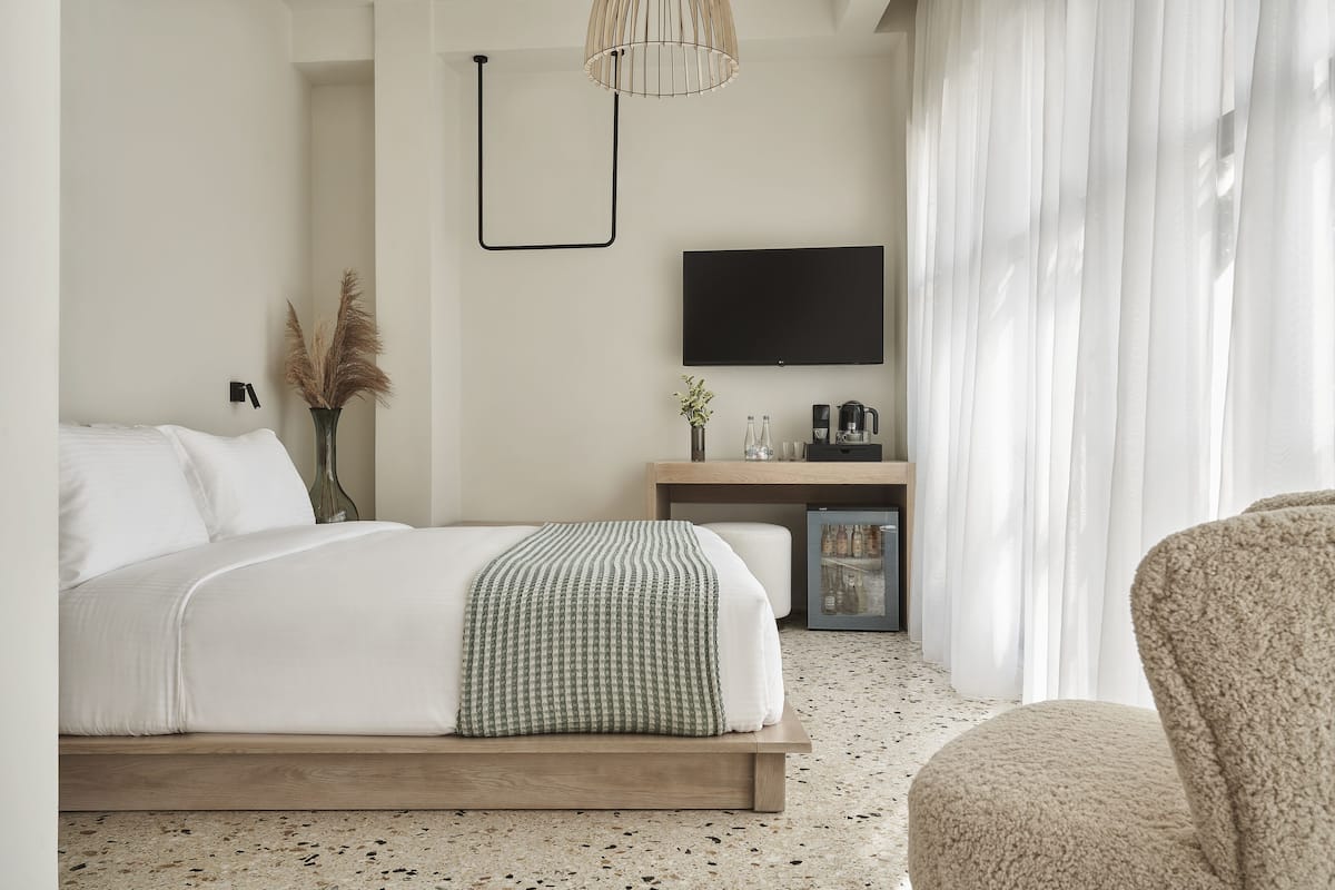 Una camera d'albergo moderna con un letto, una TV, una scrivania e una sedia.