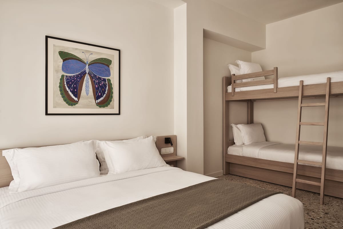 Una camera da letto con un letto a castello, un letto singolo, un quadro raffigurante una farfalla e un comodino con una lampada.