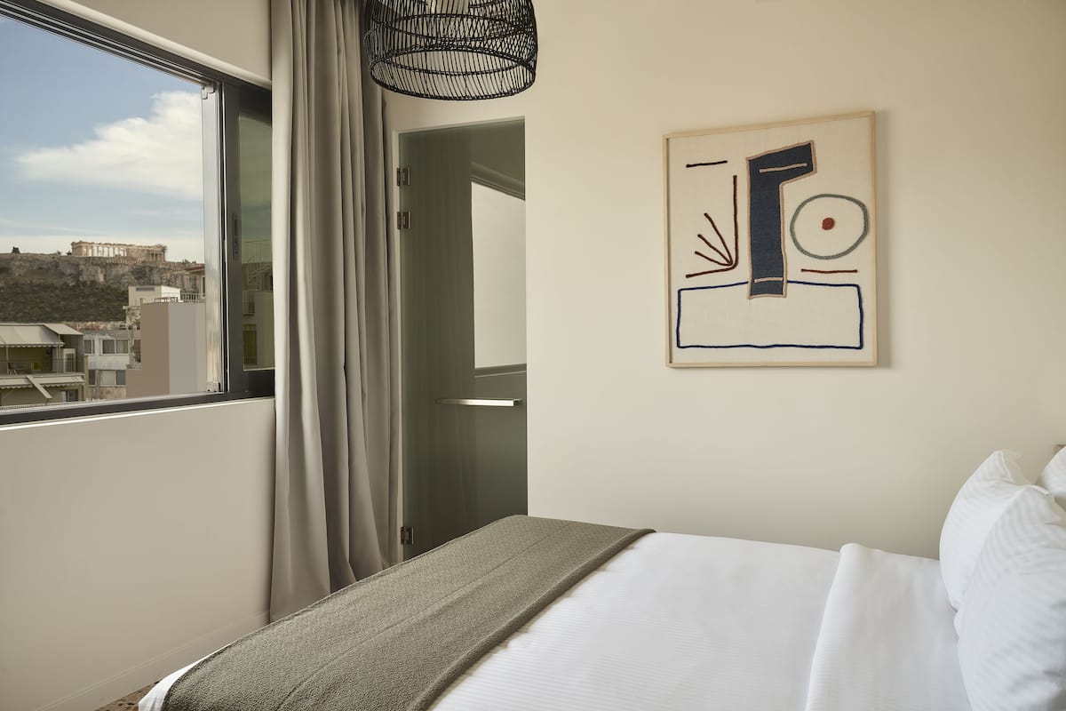Una camera d'hotel con un letto, vista sulla città e un quadro appeso al muro.
