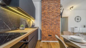 A modern kitchen with a brick accent wall, a black stove, and a wooden countertop. - 4*Flat in the Heart of the City, Onsite parking, Wifi (Split)