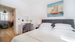 A hotel room with a large bed, a desk, and a painting of a sailboat. - 4*Flat in the Heart of the City, Onsite parking, Wifi (Split)