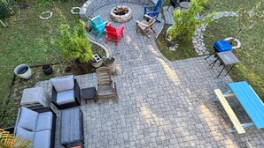 Un patio con mobiliario exterior, una fogata y una mesa azul.