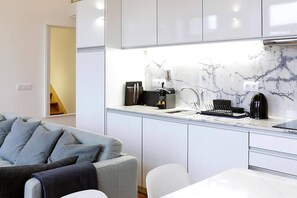 Cozy living space with a kitchenette, sofa, dining table, and chair.