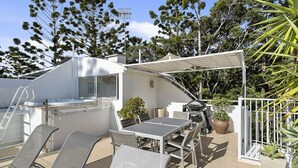 Eine Dachterrasse mit Tisch und Stühlen, einem Grill und einem Whirlpool.