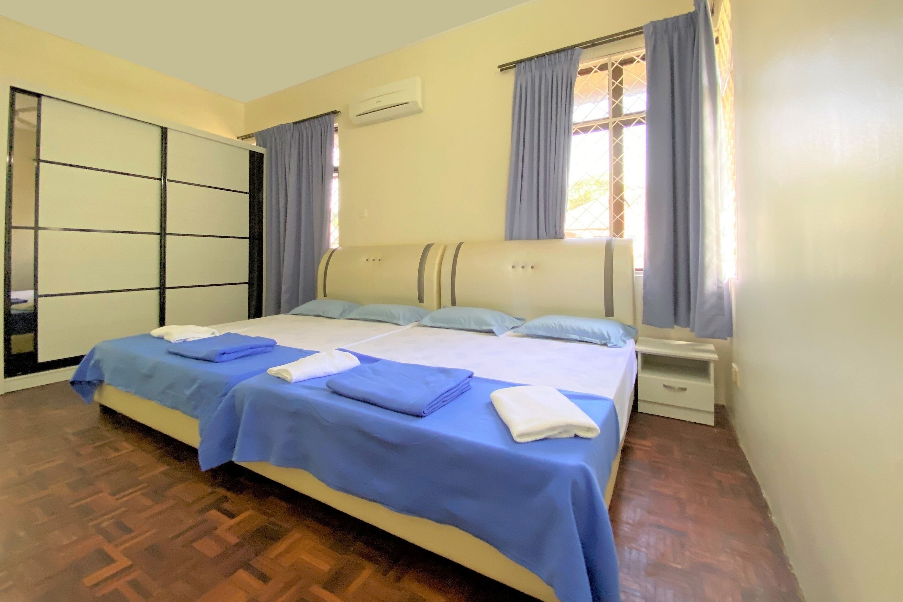 A bedroom with a large bed, a wardrobe, a nightstand, and a window with curtains.
