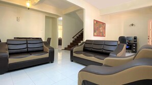 A spacious living room with two sofas, a staircase, and a television.