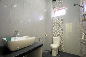 Un baño con un lavamanos blanco, inodoro y zona de ducha.