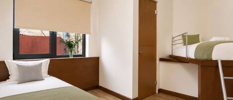 Habitación de hotel con cama, ventana con vista, puerta y una pequeña mesa con una silla.
