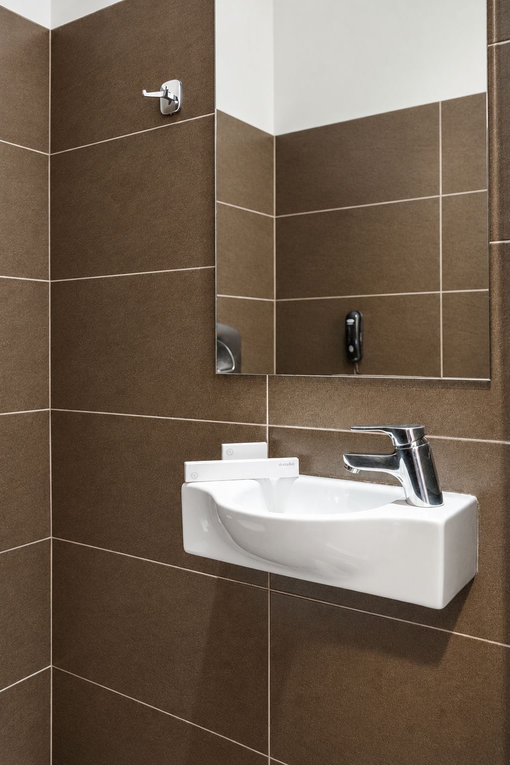 Ein Badezimmer mit einem weißen Waschbecken, einem Chrom-Wasserhahn und einem Spiegel.
