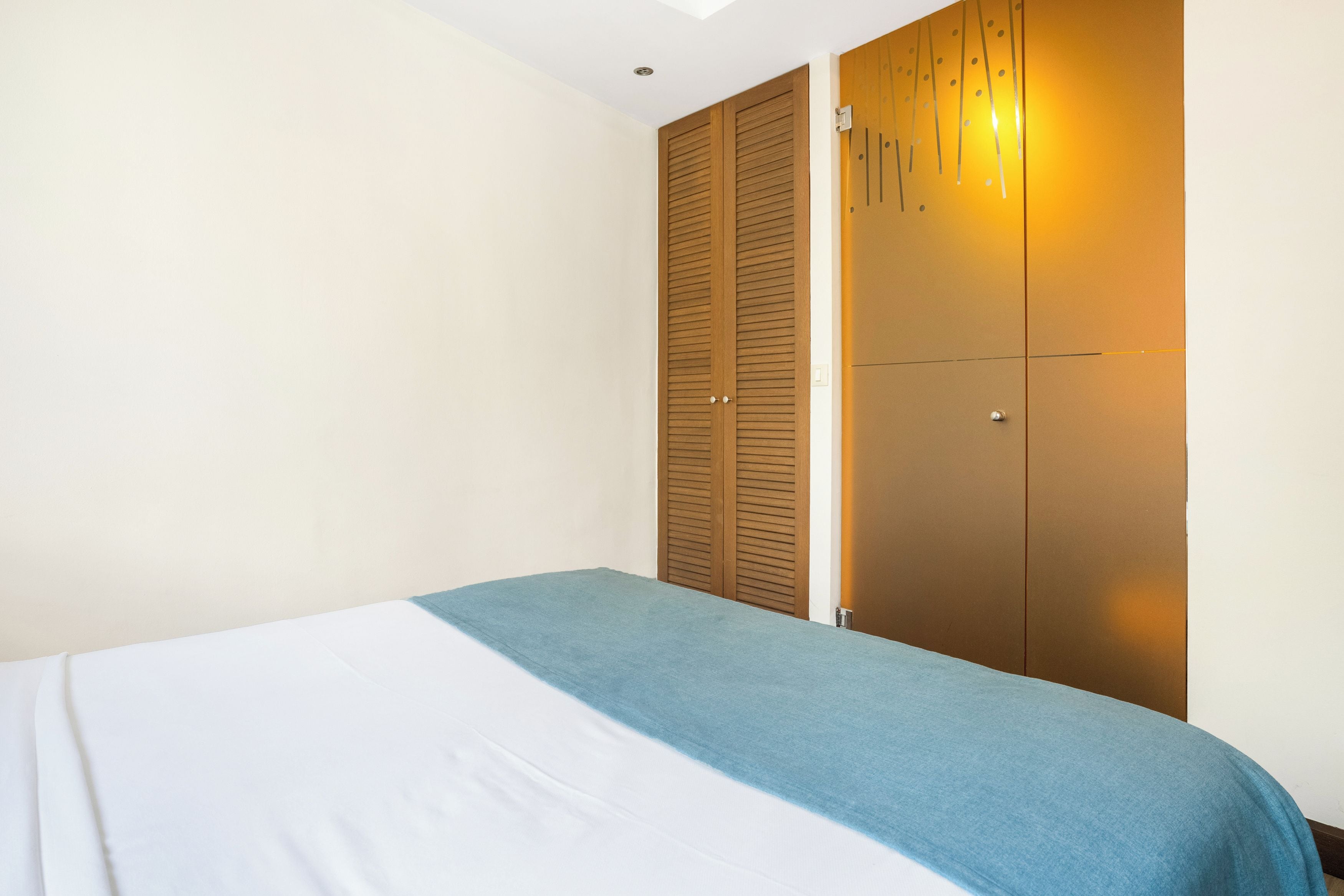 Ein Hotelzimmer mit einem Bett, einem Kleiderschrank und einer Wand mit einer Leuchte.