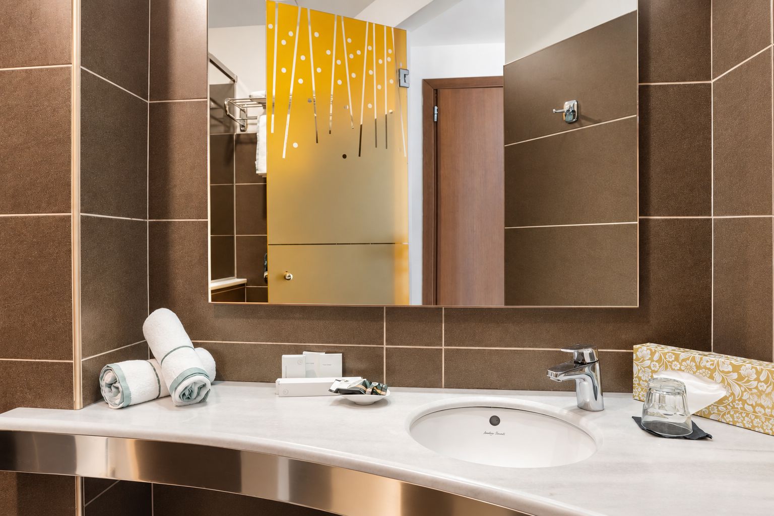Un baño moderno con un espejo grande, un lavamanos y un perchero para toallas.
