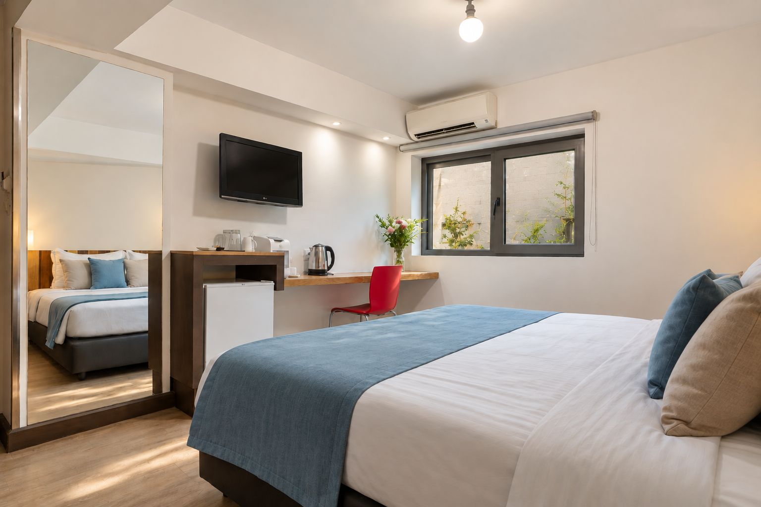 A hotel room with a bed, a desk, a chair, a TV, and a window.