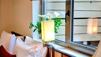 Een hotelkamer met een bed, een raam met uitzicht en een nachtkastje met een lamp en bloemen.