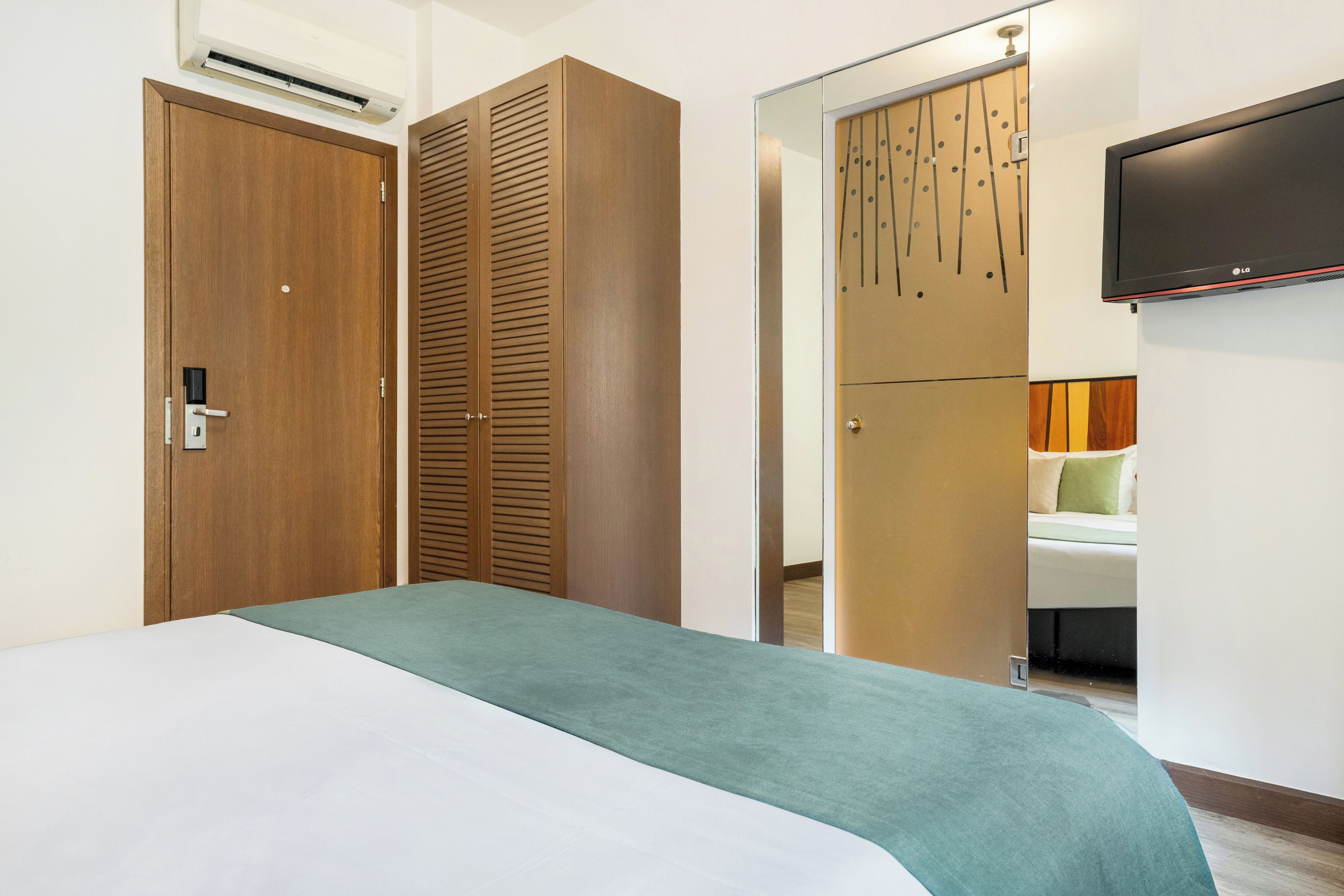 Una habitación de hotel con cama, armario y televisión en la pared.