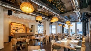 A restaurant with wooden tables and chairs, hanging lamps, and a bar area with shelves of bottles. - Lato Annex Boutique Rooms (Heraklion)