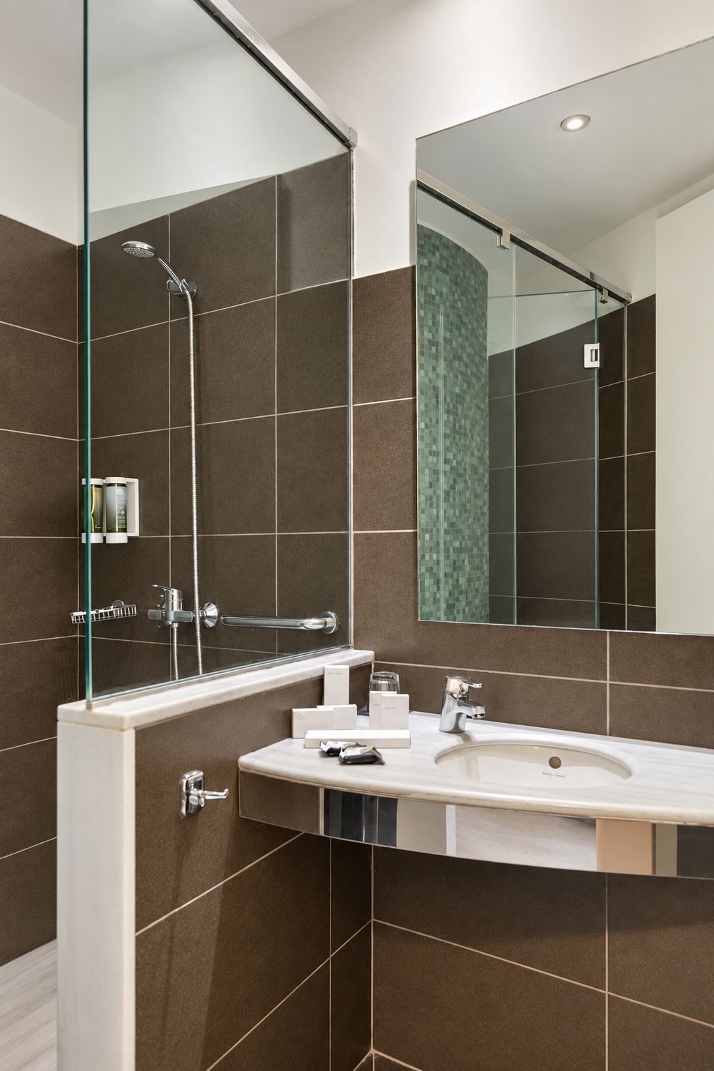 Un baño moderno con cabina de ducha de vidrio, un espejo grande y un lavabo blanco.