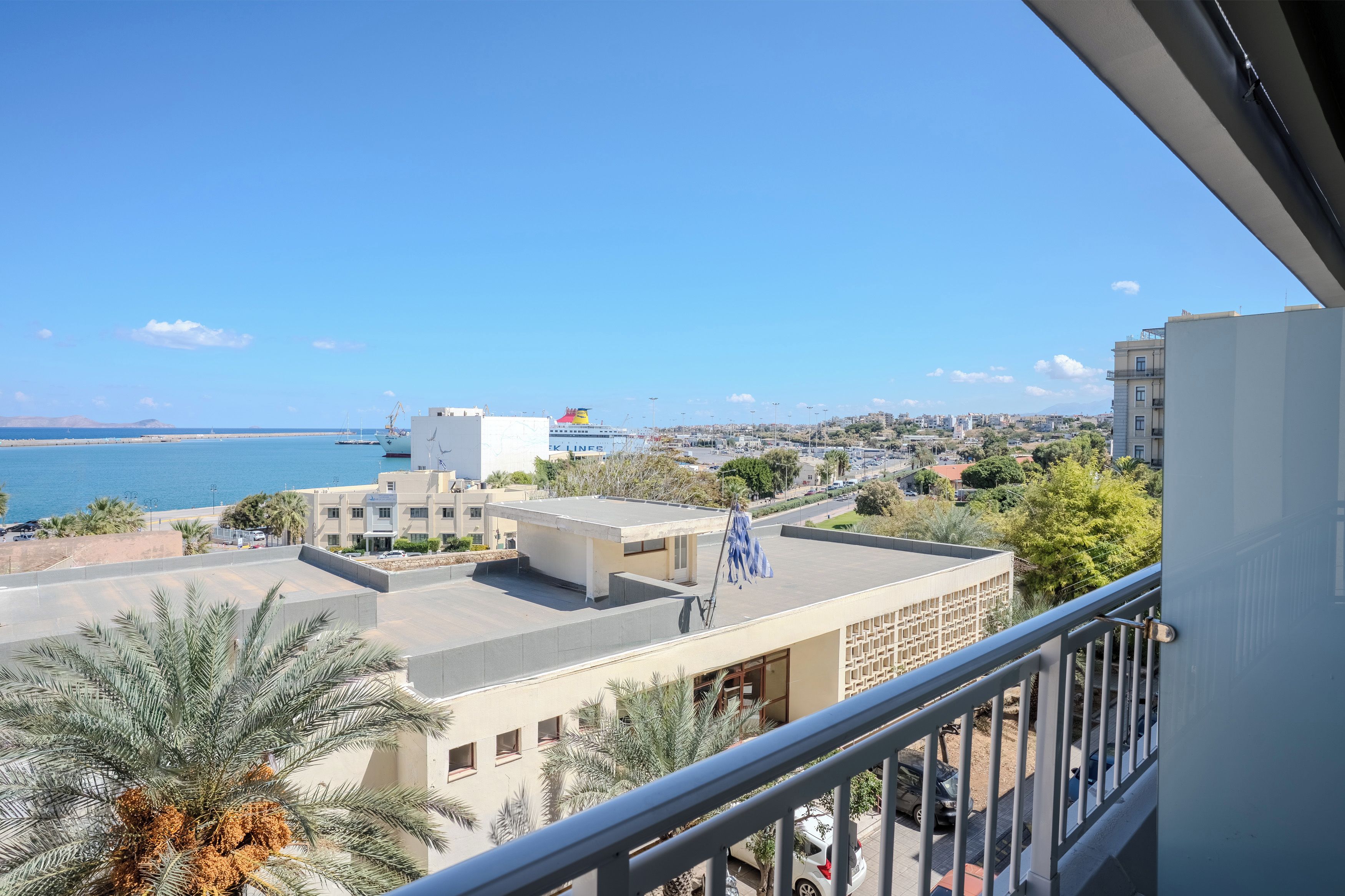A coastal cityscape with a view of the sea, buildings, and a clear sky.