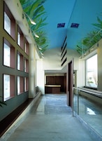 Un corridoio con un affresco al soffitto, una reception e una ringhiera in vetro.