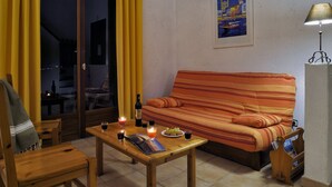 Un salon chaleureux avec un canapé, une table en bois sur laquelle sont posées des boissons et une lampe.