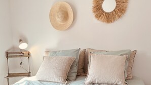 A bed with a quilt, pillows, a wall-mounted hat, and a mirror. - Beach House (Lège-Cap-Ferret)
