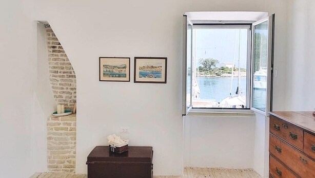 A room with a stone wall, a window with a view of a body of water, and a wooden floor. - Dolce Vivere by Konnect, Gaios Paxos (Paxos)