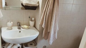 A compact bathroom with a white sink, a mirror, a towel rack, a toilet, and a trash bin. - Dolce Vivere by Konnect, Gaios Paxos (Paxos)