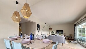 A dining area with a round table, light blue chairs, and hanging pendant lights. - Modern villa with private pool and garden (Mar de Cristal)