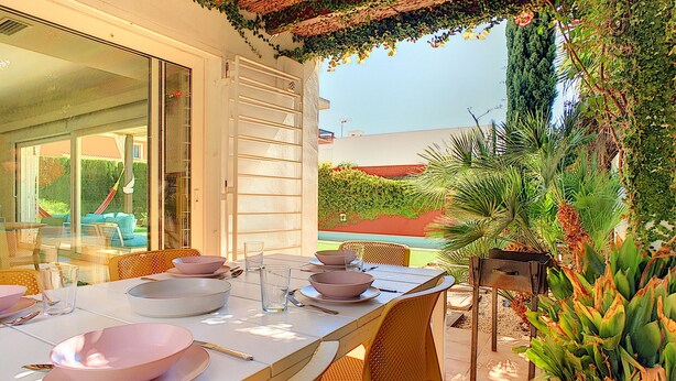 An outdoor dining area with a table set for four, surrounded by greenery and a view of the garden. - Modern villa with private pool and garden (Mar de Cristal)