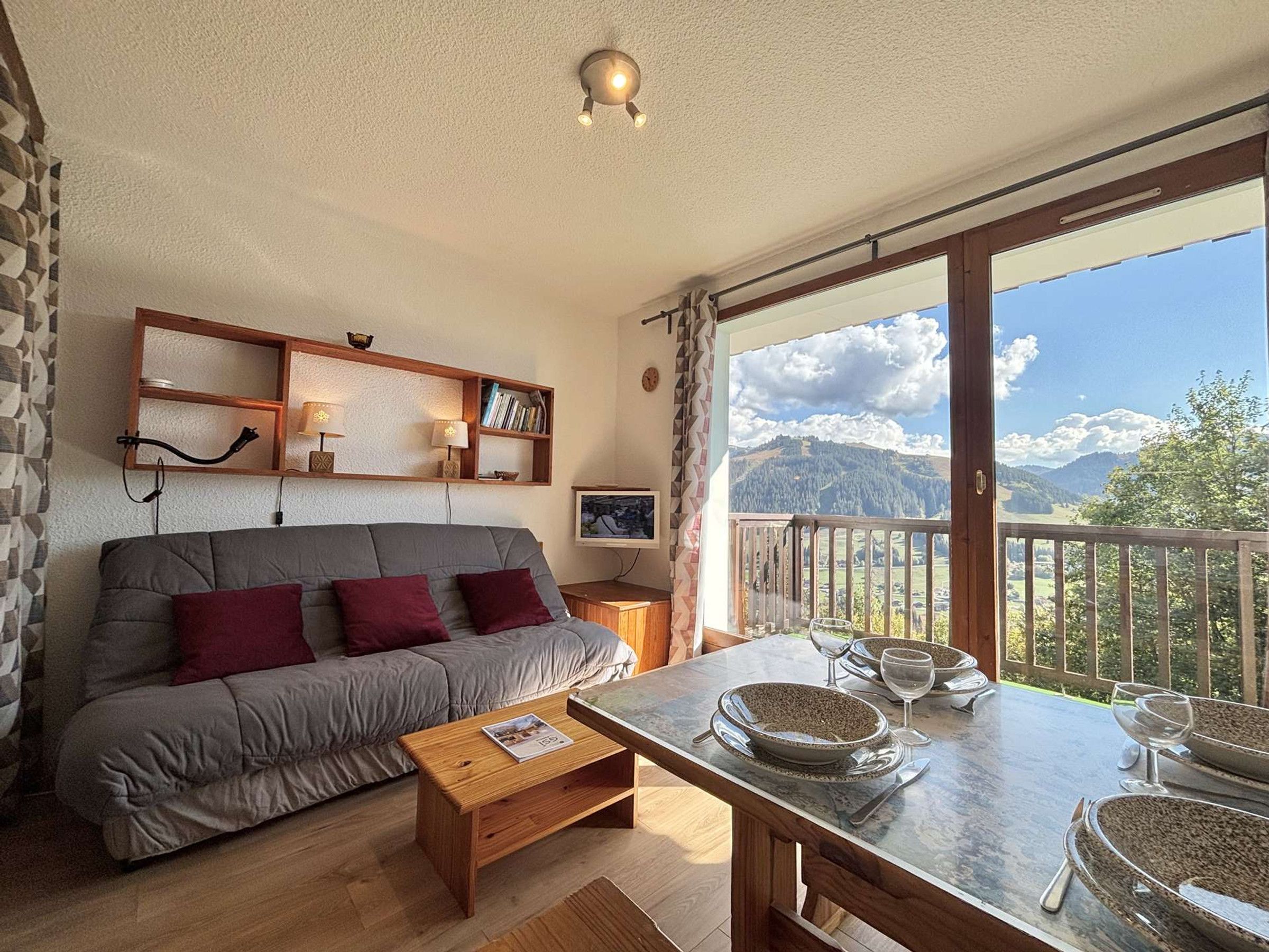 Un salon chaleureux avec un canapé, une table basse et une table à manger pour deux personnes, offrant une vue imprenable sur les montagnes.