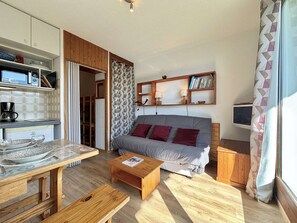 A compact living space with a kitchenette, a sofa with cushions, a coffee table, and a television. - Cozy studio in Notre-Dame-de-Bellecombe with parking and easy access to the slopes (Notre-Dame-de-Bellecombe)