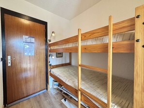Ein Schlafraum mit Etagenbetten, einer Holztür und einer Lampe.