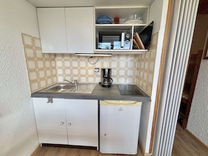Eine kleine Küchenzeile mit Spüle, Kaffeemaschine und Mikrowelle.