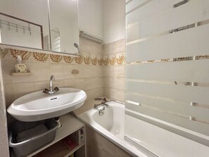 A bathroom with a white sink, a mirror, a shower, and a toilet.