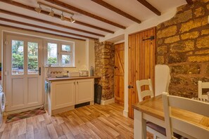 Eine Küche mit Holzbalken, einer Steinwand und einer Holztür.