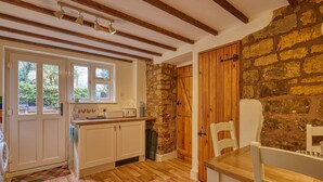 Une cuisine avec des poutres en bois, des murs en pierre et une porte en bois.