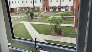 A view of a courtyard with a building in the background. - Toothbrush Apartments - 2 Bed 1 Bath Apt (Ipswich)