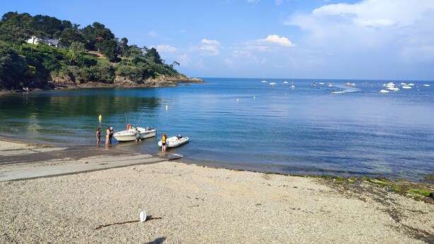 Une plage avec des bateaux, une côte rocheuse et une maison située sur une colline.