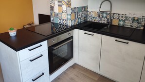 Une cuisine moderne avec un plan de travail noir, des armoires blanches et un pare-feu décoré de motifs.