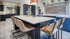 A modern kitchen with a central island, bar stools, and a pendant light. - Cilrhiw Country House - Narberth (Narberth)